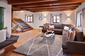 Ein gemütliches Wohnzimmer mit einer Sofagarnitur, einem Couchtisch und einer Treppe, die in einen oberen Bereich führt.