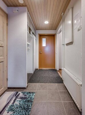 A hallway with a wooden ceiling, a carpeted entrance, and a door at the end. - Länsirinne C9 | Modern 2BR Apt with Lake Views (Ruka)