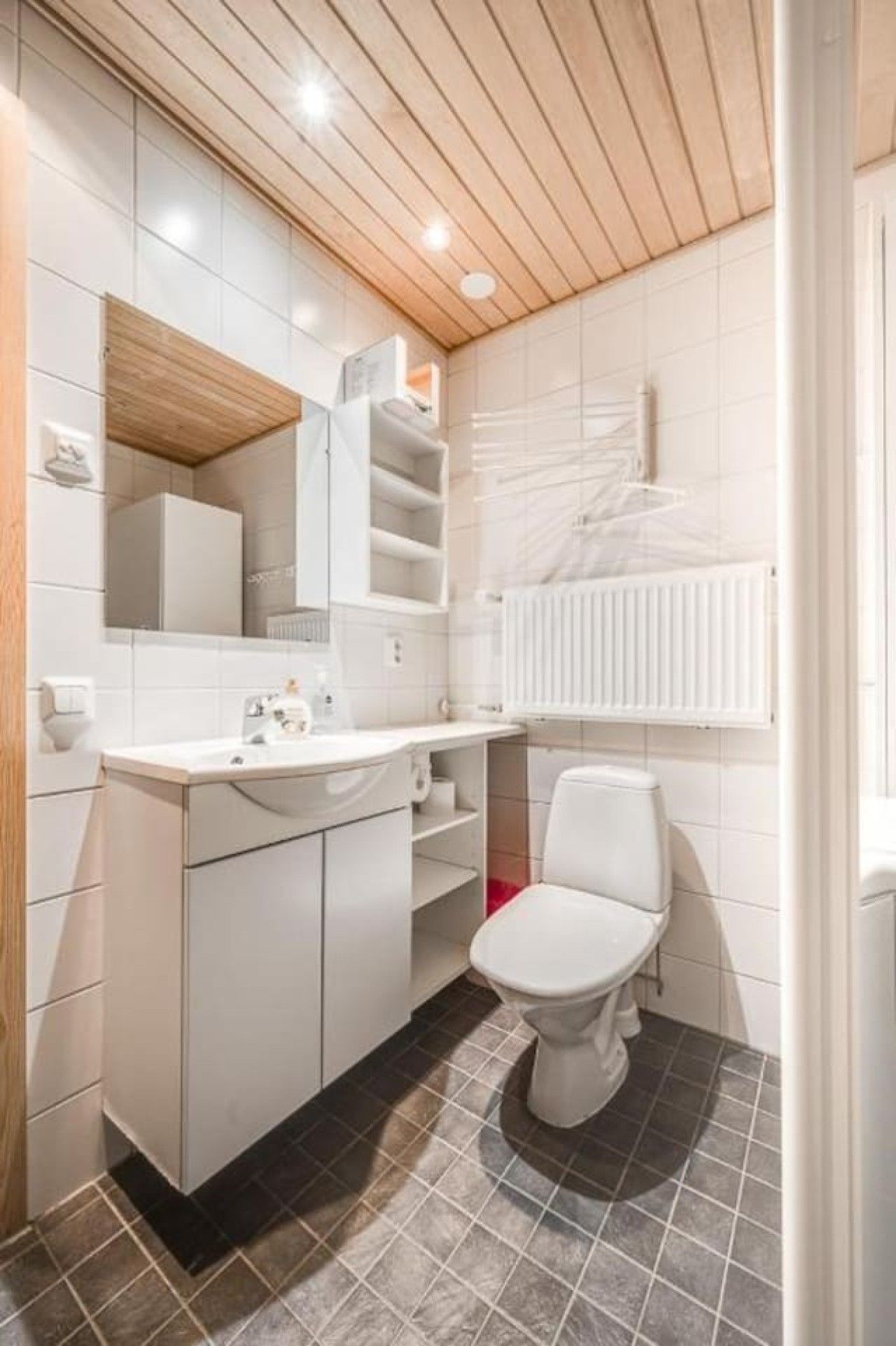 Een kleine badkamer met een wit toilet, een wastafel en een spiegel.