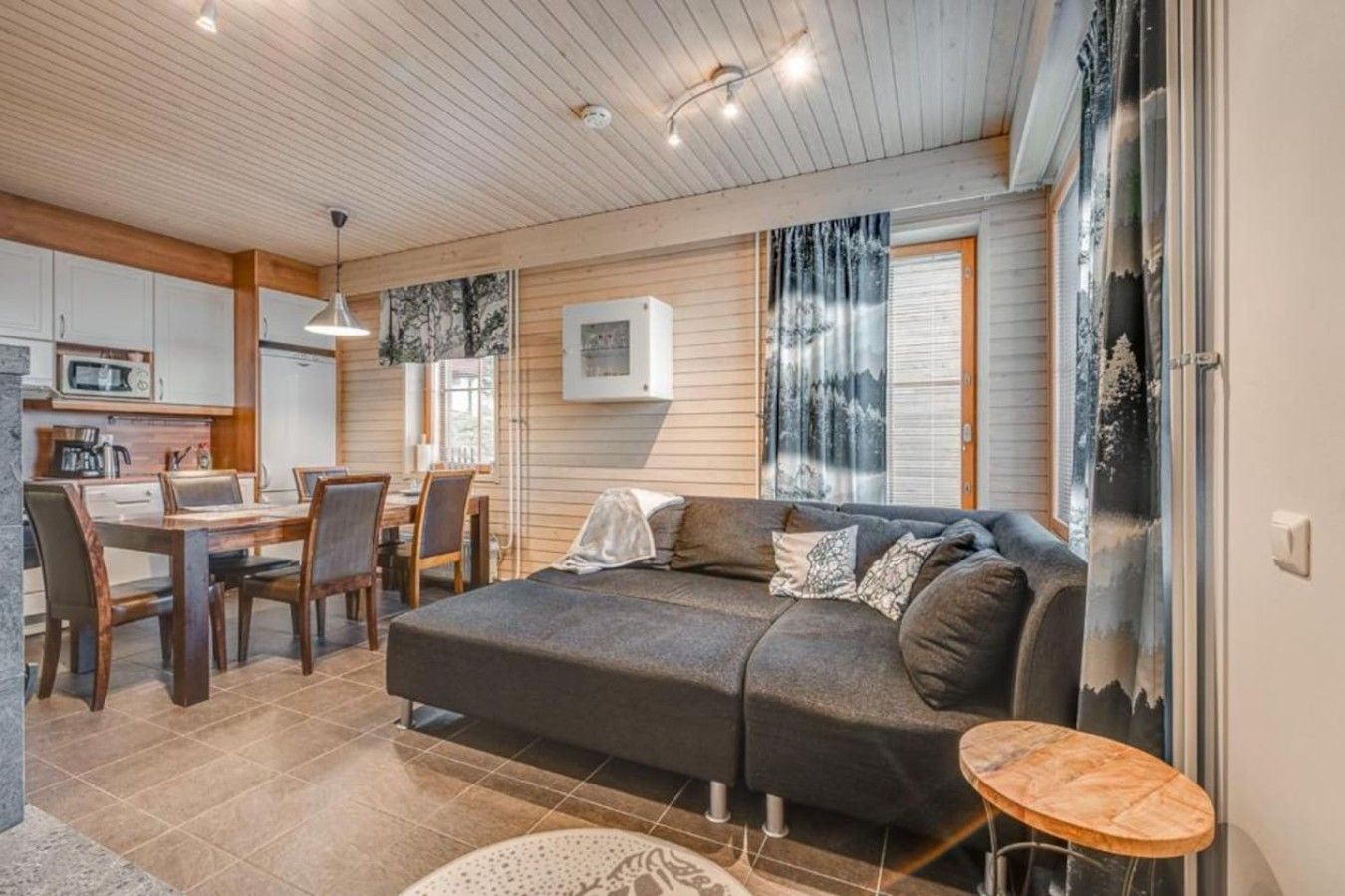 Ein gemütlicher Wohnbereich mit einer Couch, einem Esstisch und Stühlen, einer Küchenzeile mit einer Mikrowelle und einem großen Fenster mit Blick.