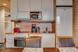 A compact kitchenette with a microwave, coffee maker, toaster, and a refrigerator. - Länsirinne C9 | Modern 2BR Apt with Lake Views (Ruka)