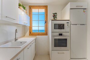 Eine kleine Küche mit Fenster, einem Kühlschrank von Bosch und einer Spüle.