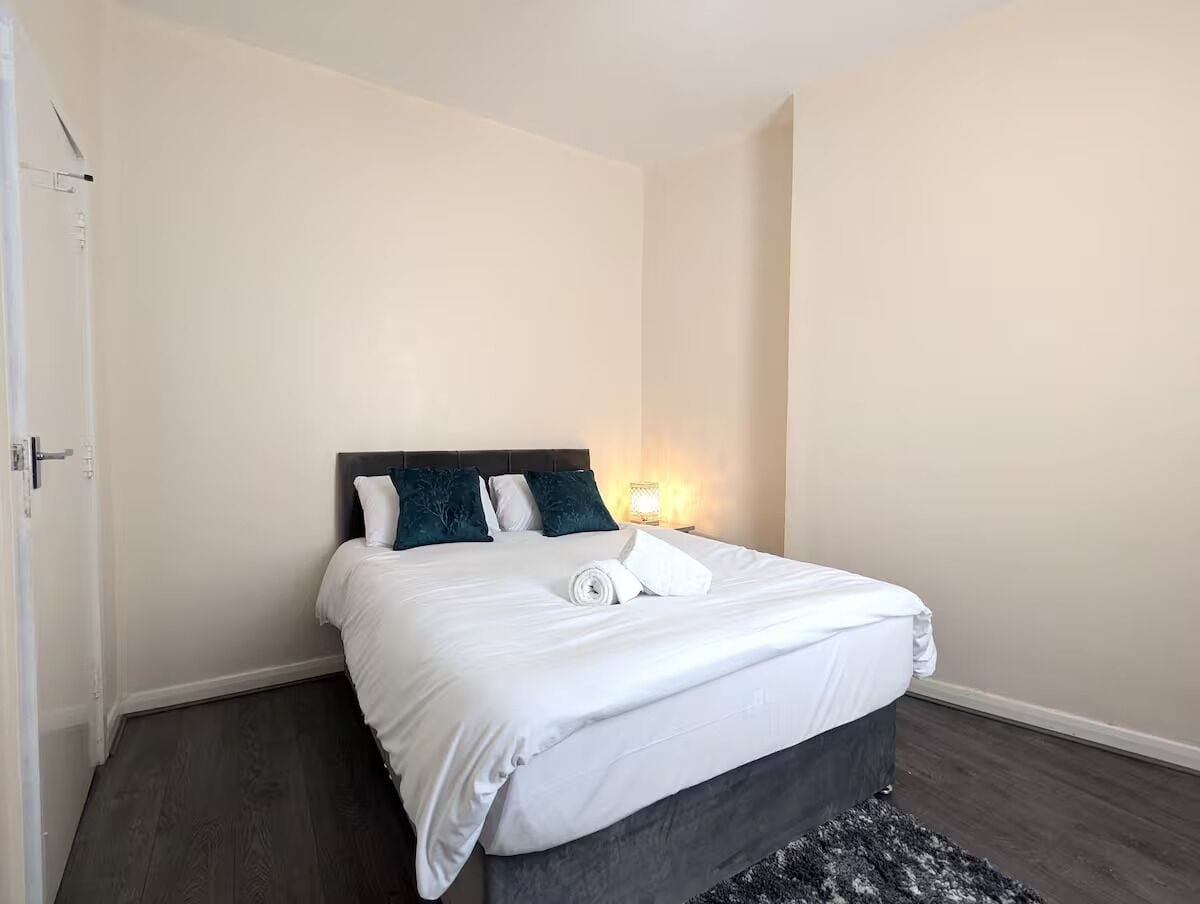A hotel room with a bed, a nightstand, and a wall-mounted lamp.