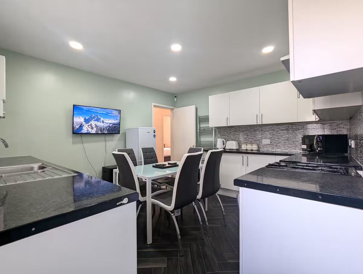 A modern kitchen with a dining area, a flat-screen TV, and a built-in oven.