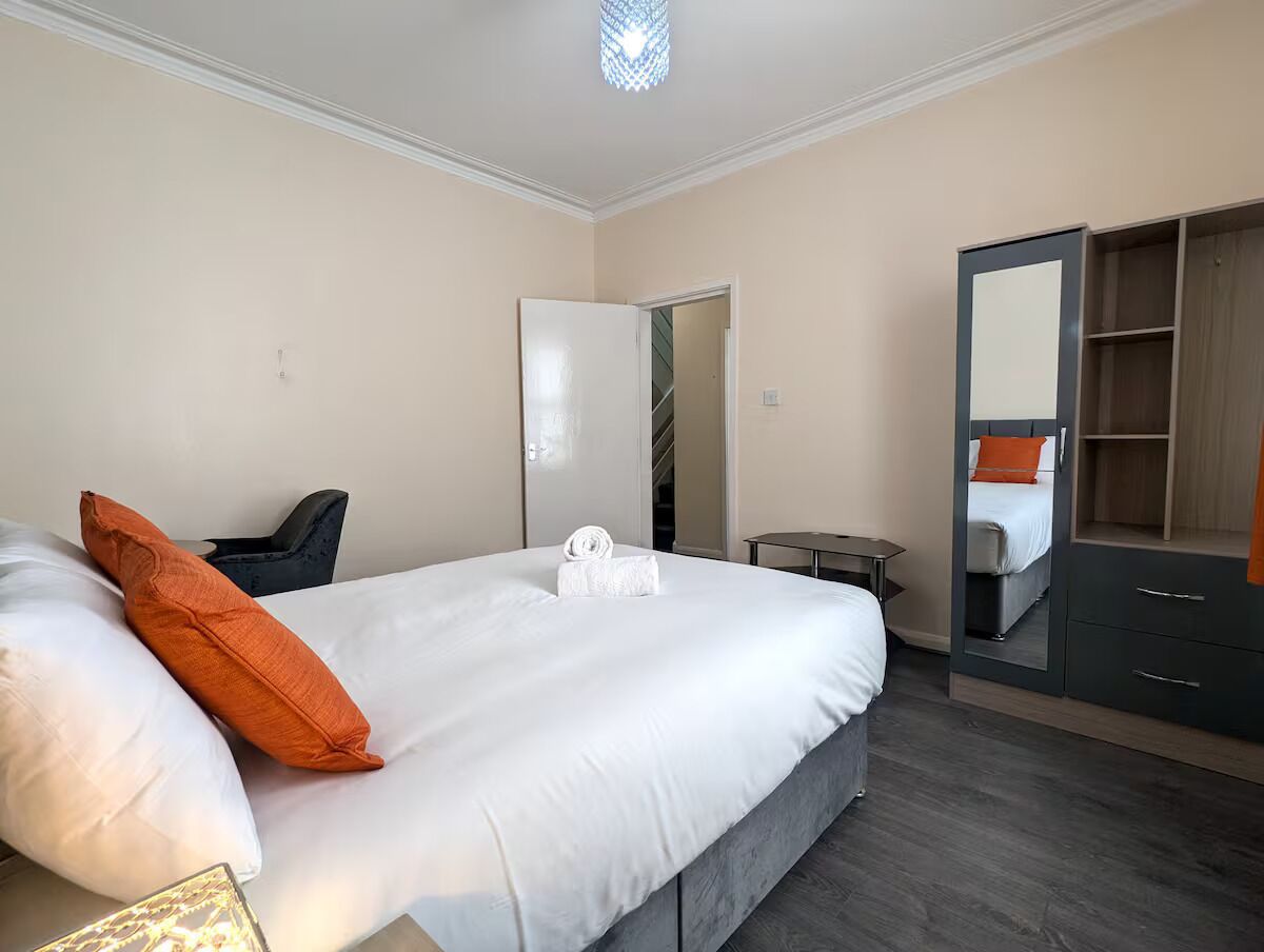 A hotel room with a bed, a wardrobe, and a small table.