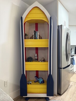 A corner kitchen with a built-in bookshelf, a refrigerator, and a small plant. - Serene Key Largo Gem (Key Largo)