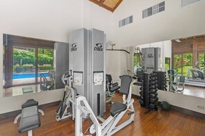 A gym with various exercise equipment, including a leg press machine, a seated leg press, and dumbbells. - Hermosa del Mar 1-6B | Ocean Views, Walk to Beach (Playa Hermosa)