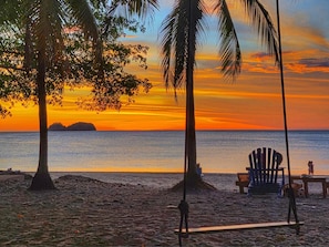 A beach scene with palm trees, a chair, and a bench. - Hermosa del Mar 1-6B | Ocean Views, Walk to Beach (Playa Hermosa)