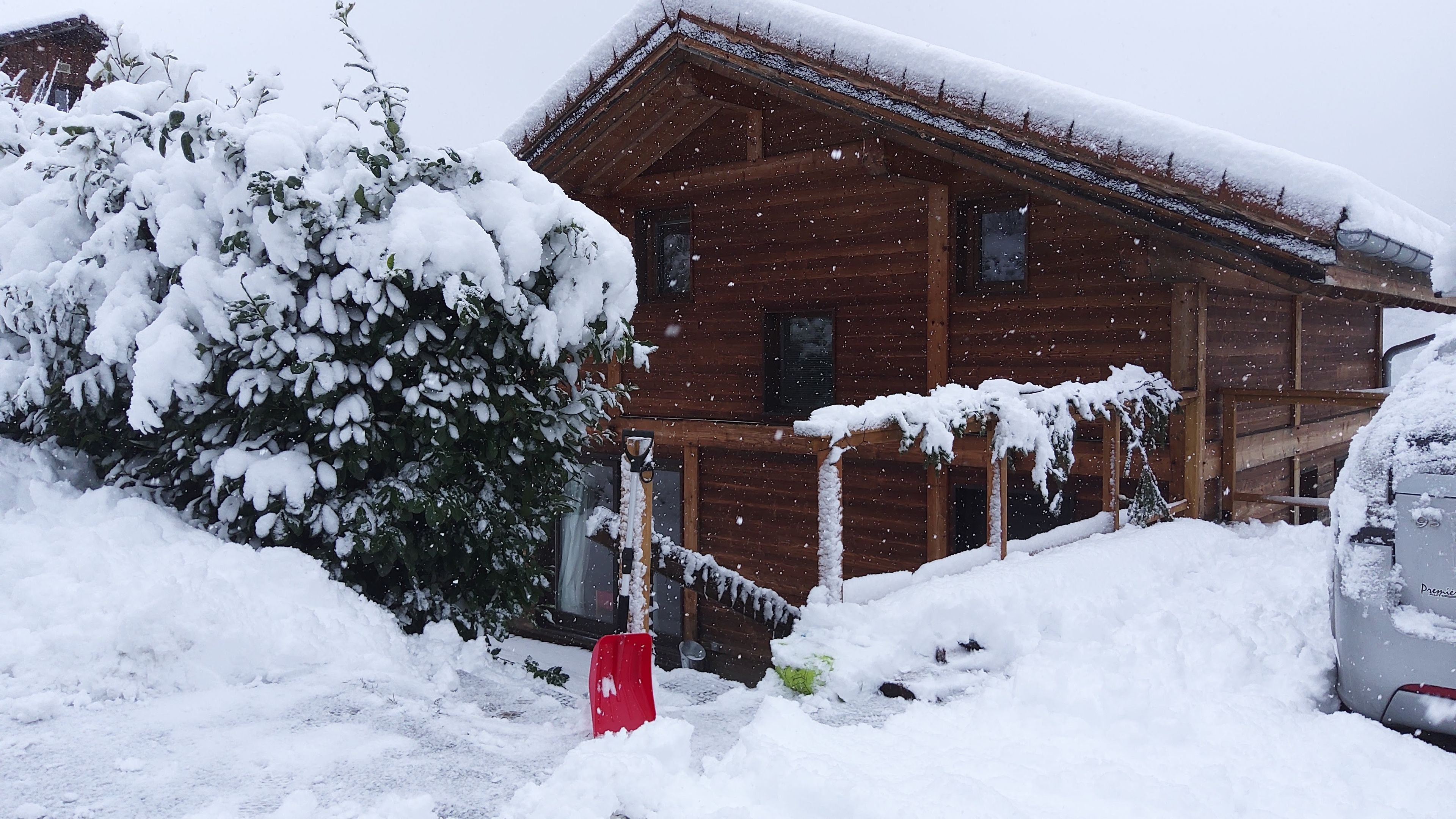 Una cabaña de madera con techo nevado y un buzón rojo en primer plano.