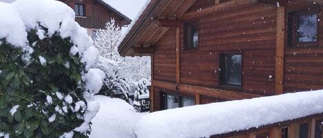 Una cabaña de madera con techo nevado y terraza de madera.