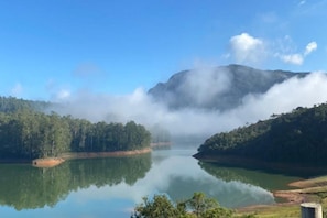 A calm lake surrounded by forested hills, with a clear sky above.
