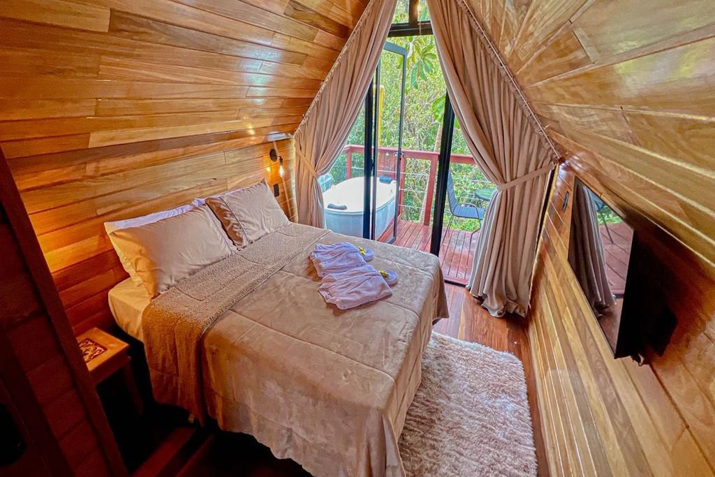 A cozy bedroom with a bed, a nightstand, and a window with curtains.