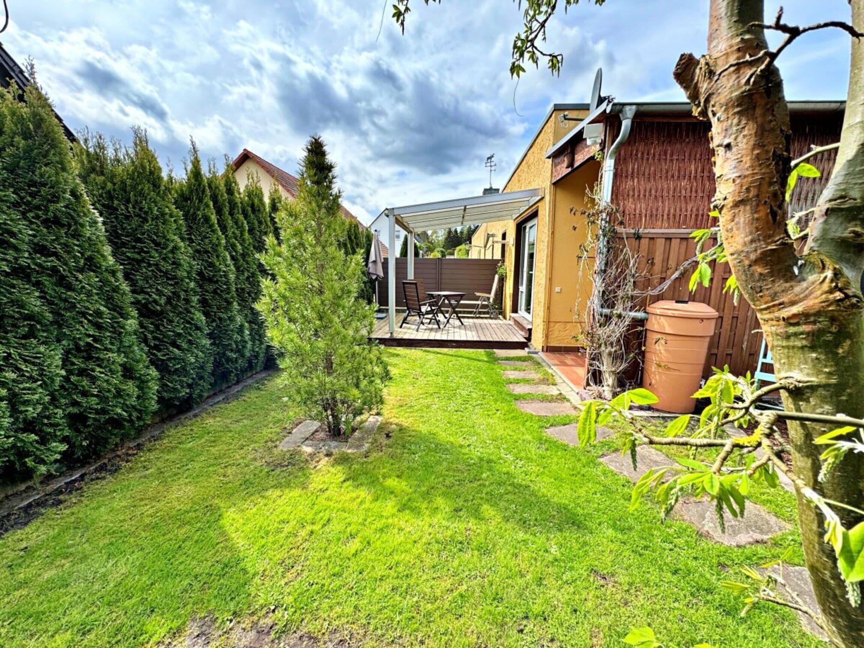 A backyard with a patio, a small tree, and a wooden fence.