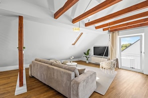A modern living room with a sofa, a TV, and a hanging chair.