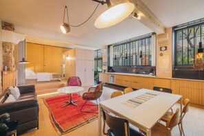 Une cuisine moderne avec des meubles en bois, un coin repas comprenant une table et des chaises, et une grande fenêtre donnant sur un paysage verdoyant.