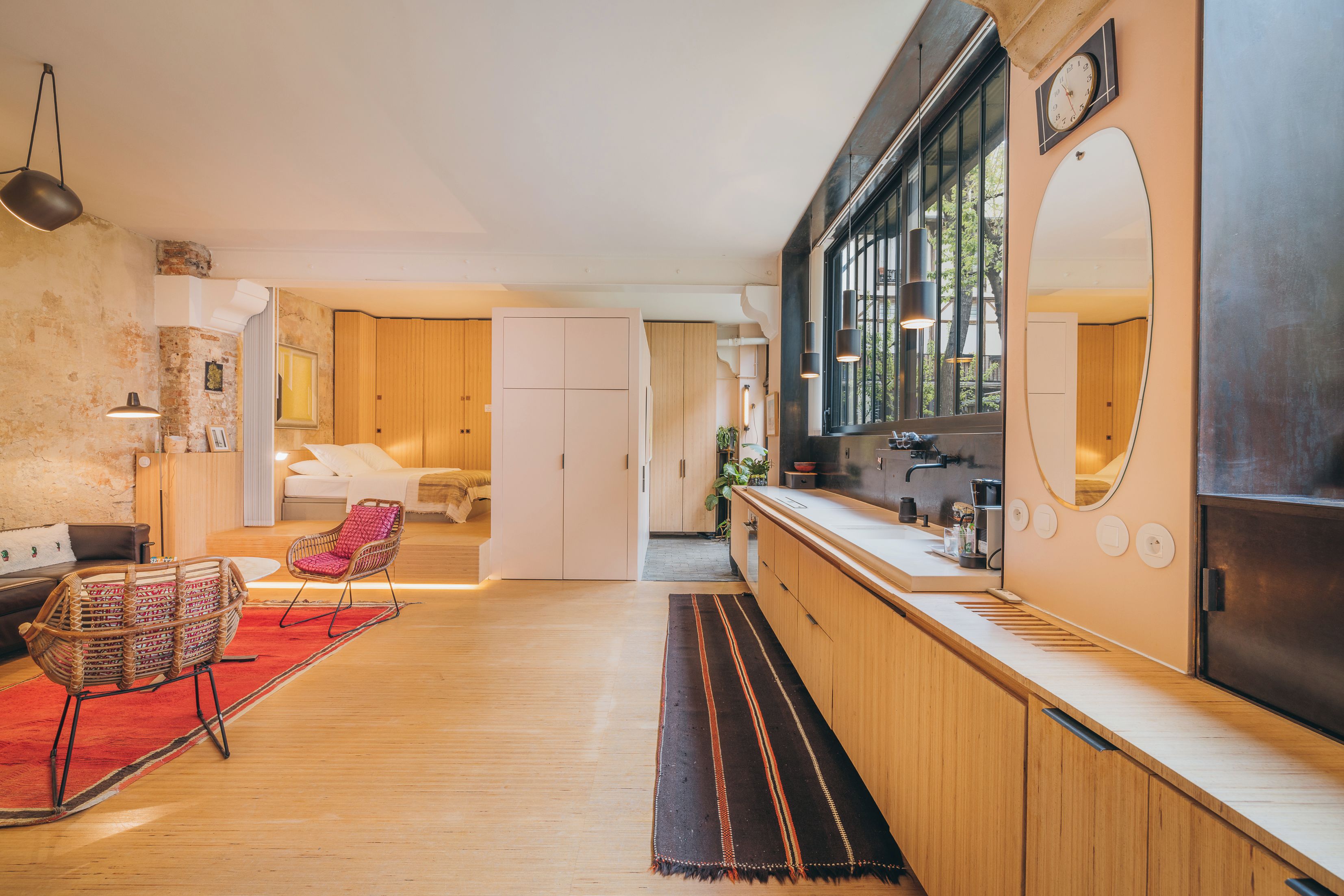 A modern interior with a kitchen, dining area, and a living room with a sofa and a chair.