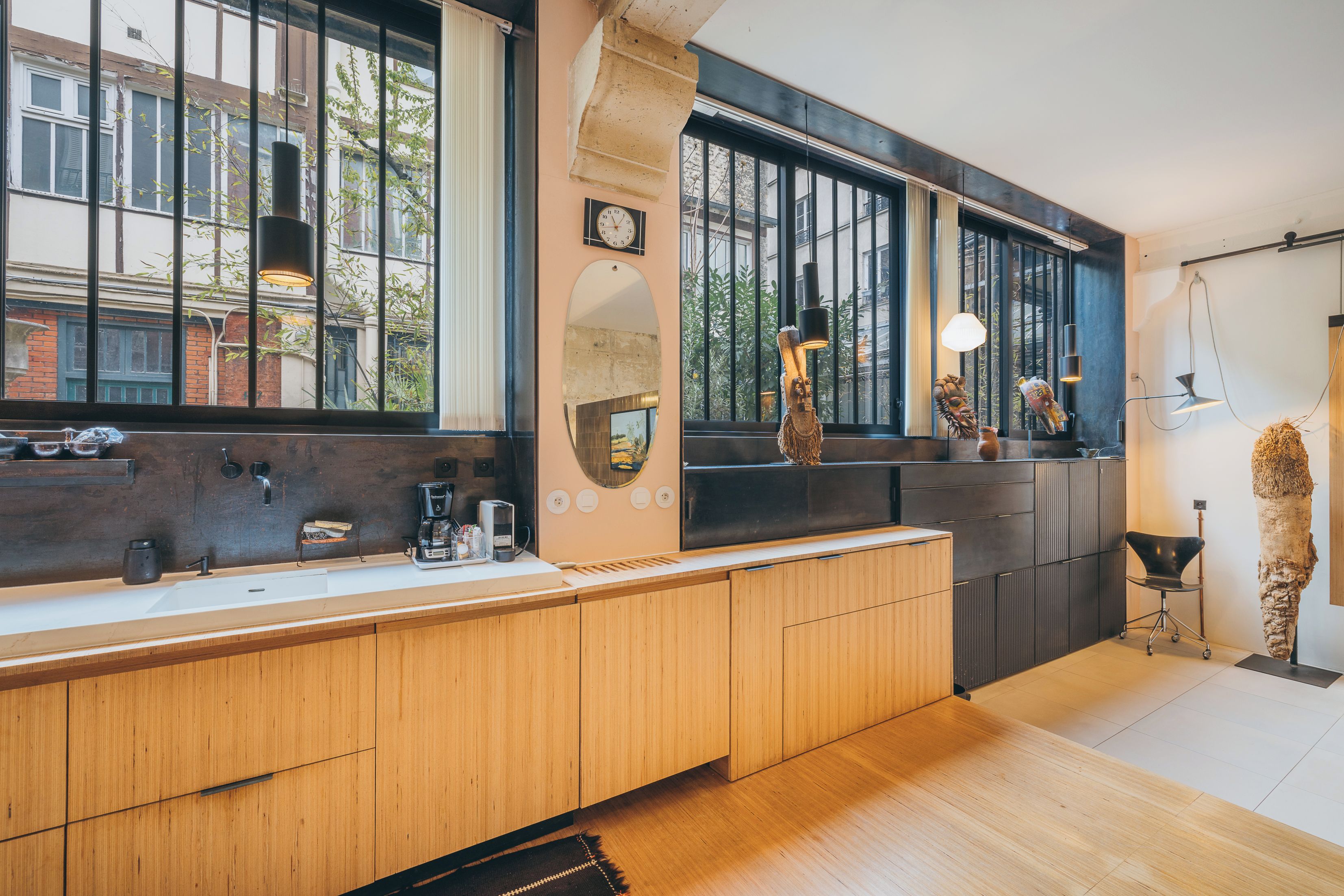 Une cuisine moderne avec des meubles en bois, un four encastré et une grande fenêtre donnant sur un paysage urbain.