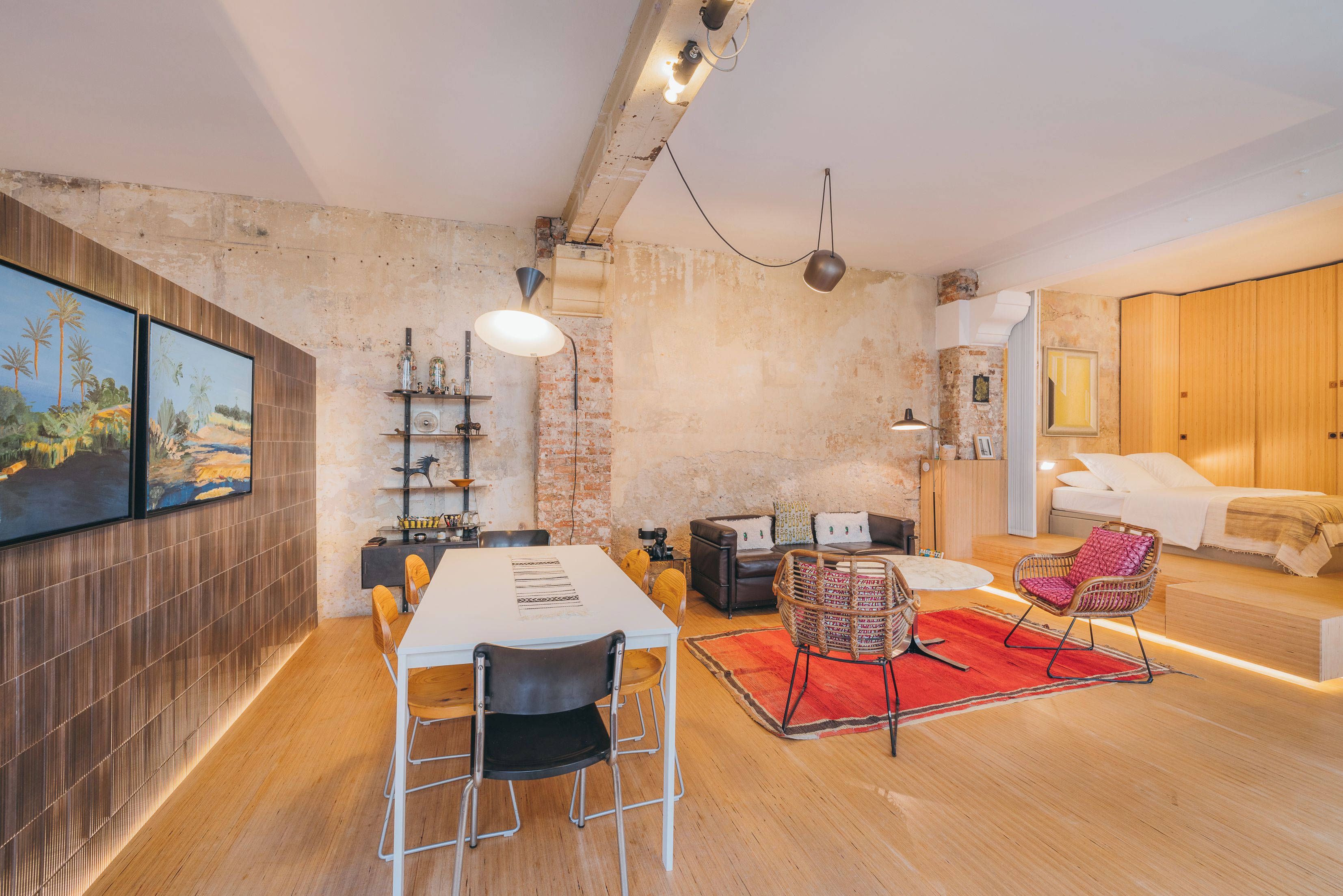 Een ruime woonkamer met een eettafel, stoelen, een bank en een rood vloerkleed.