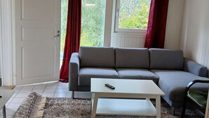Una sala de estar con un sofá gris, una mesa de centro blanca y un tapiz estampado.