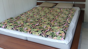 Una cama con colcha estampada, cabecera de madera y dos almohadas.