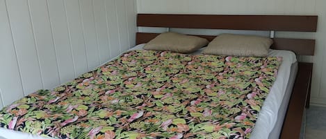 Una cama con colcha estampada, cabecera de madera y dos almohadas.