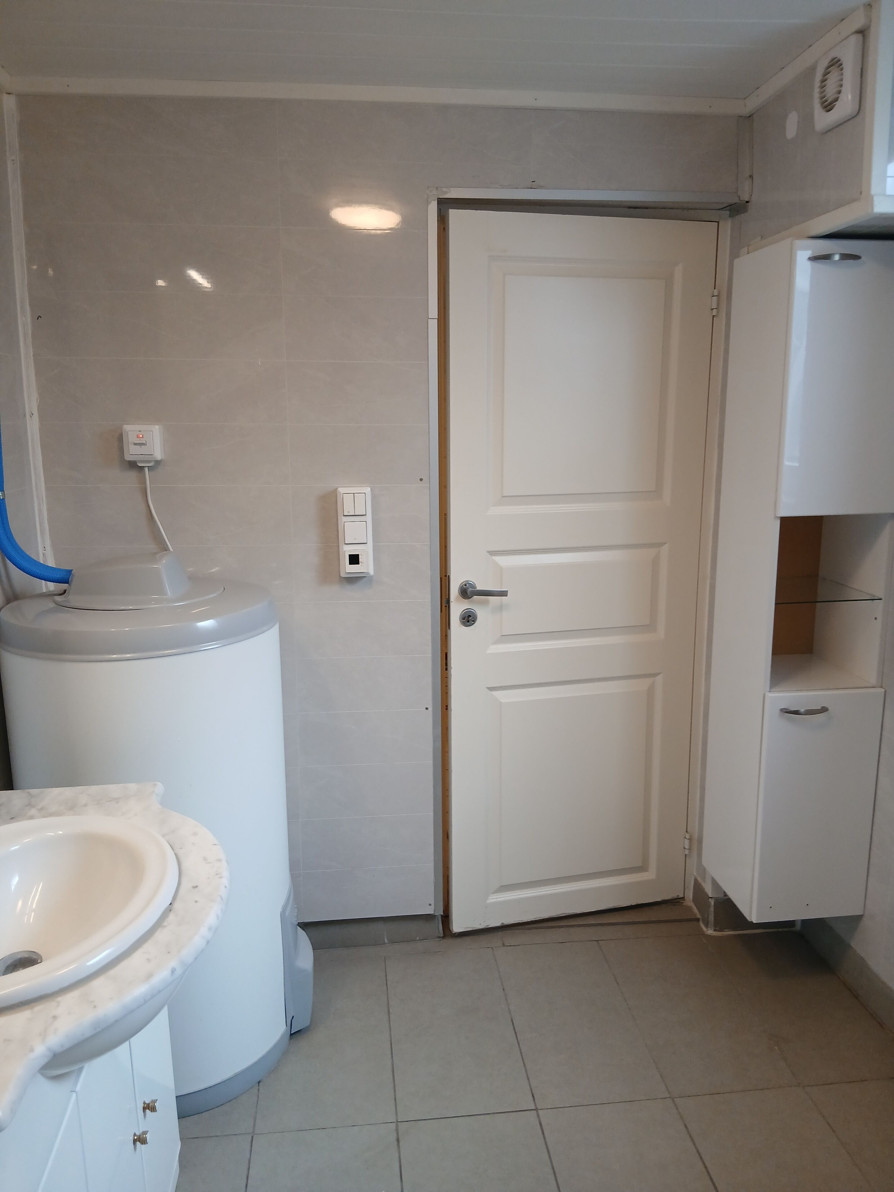 Un baño con inodoro, lavamanos y una puerta blanca.