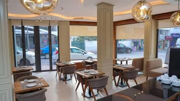 Un intérieur de restaurant moderne avec des tables, des chaises et des luminaires suspendus.