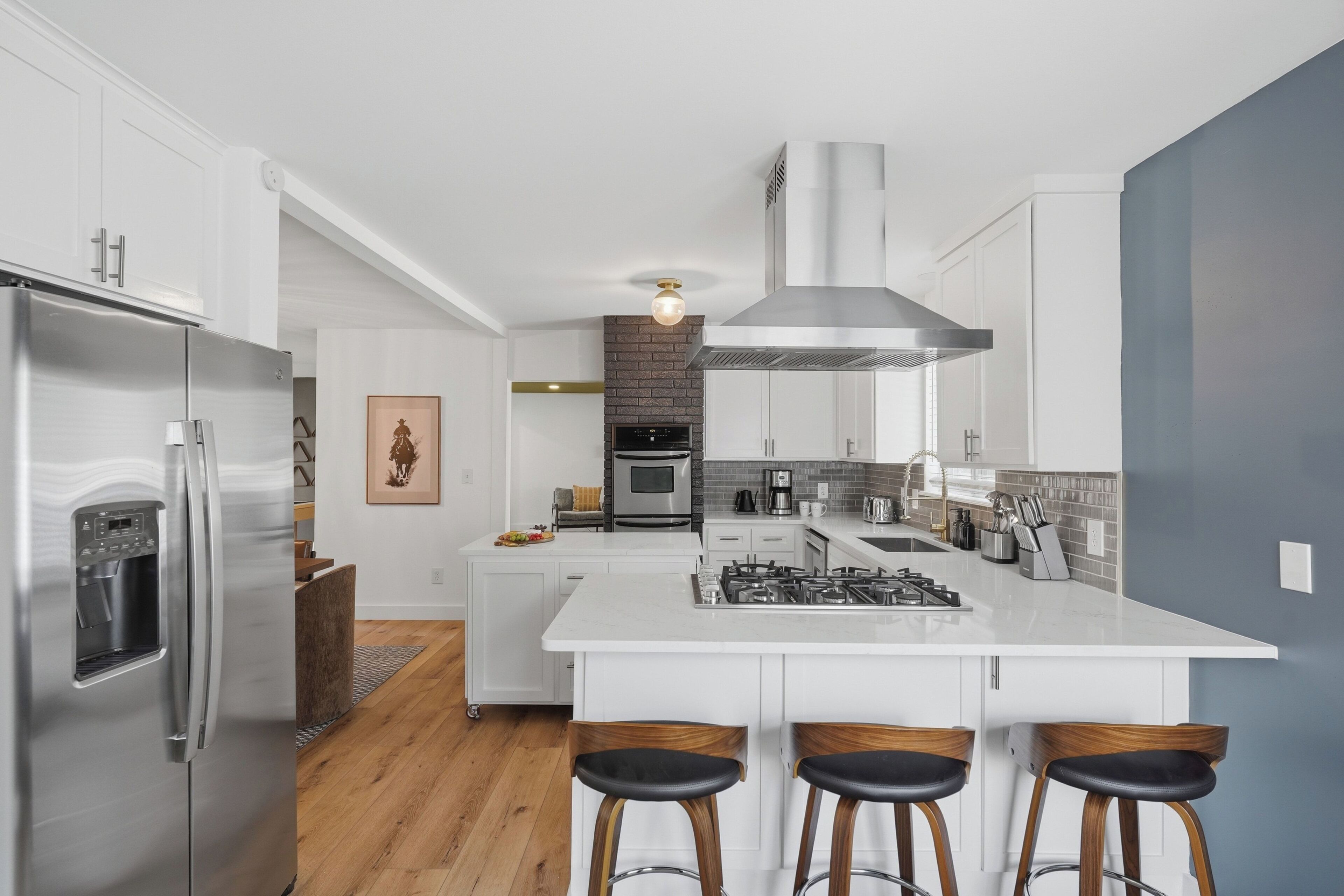 A modern kitchen with a central island, stainless steel appliances, and a brick backsplash.