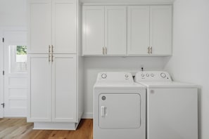 A laundry room with white cabinets and a front-loading washer and dryer.