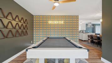 A pool table in a room with a patterned wall and a ceiling fan.