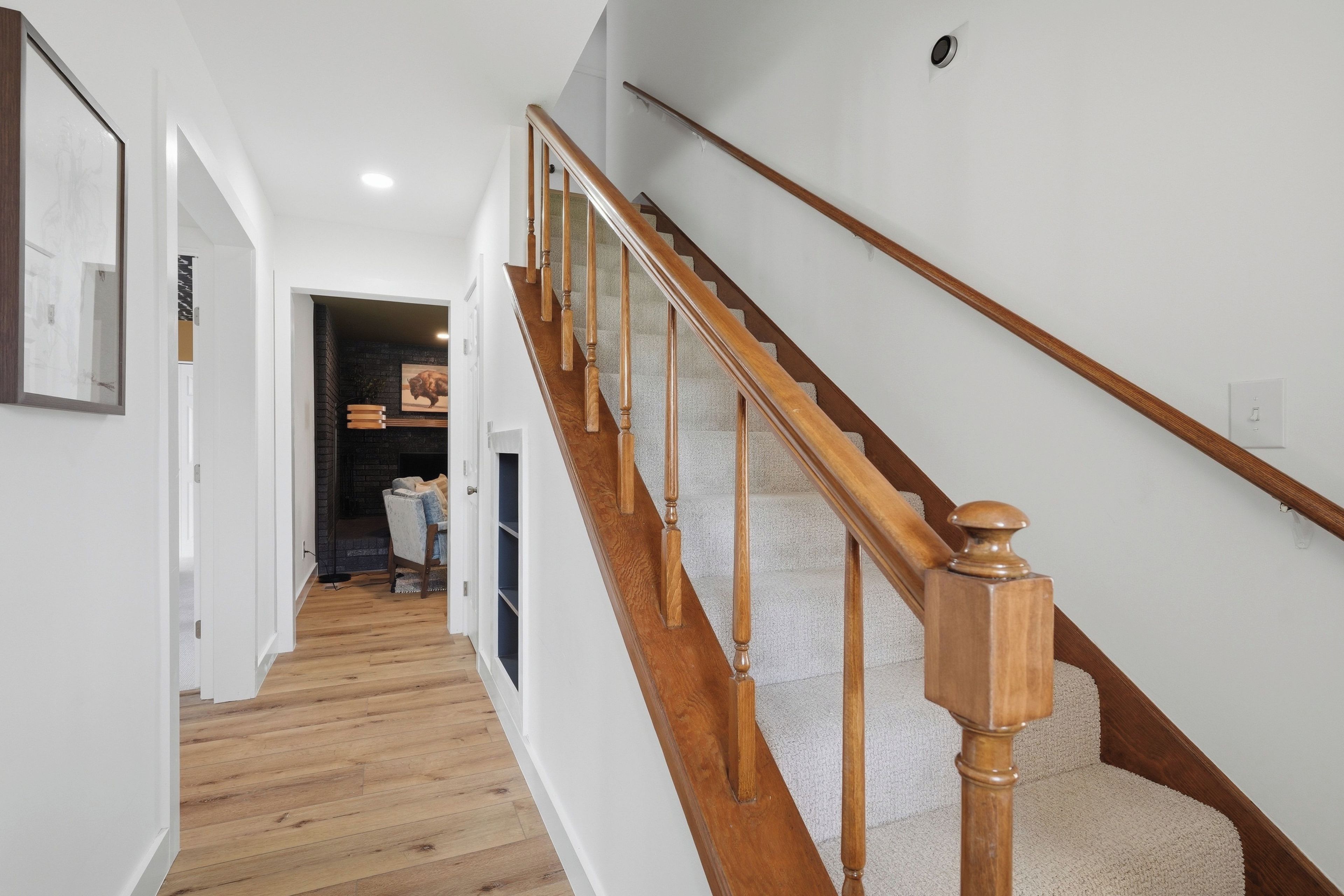 Una escalera con barandillas de madera y peldaños alfombrados que conducen a una plataforma.