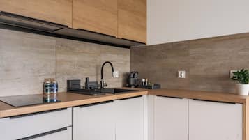 A modern kitchen with a wooden countertop, a sink, and a coffee maker.
