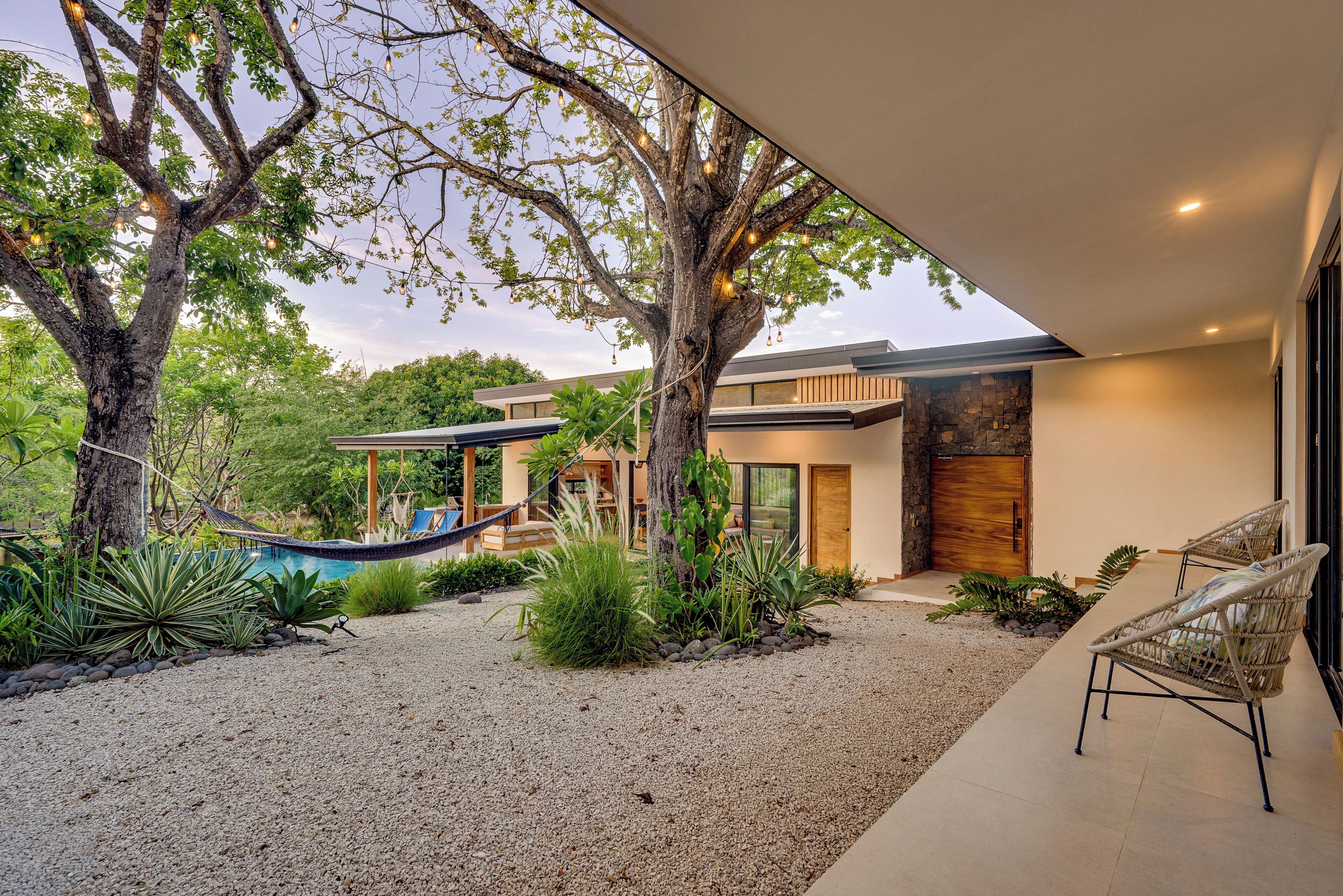 A modern house with a pool, outdoor seating, and a hammock.