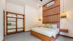Una camera da letto con una struttura letto in legno, un armadio a muro, un condizionatore d'aria fissato alla parete e due lampade a sospensione.