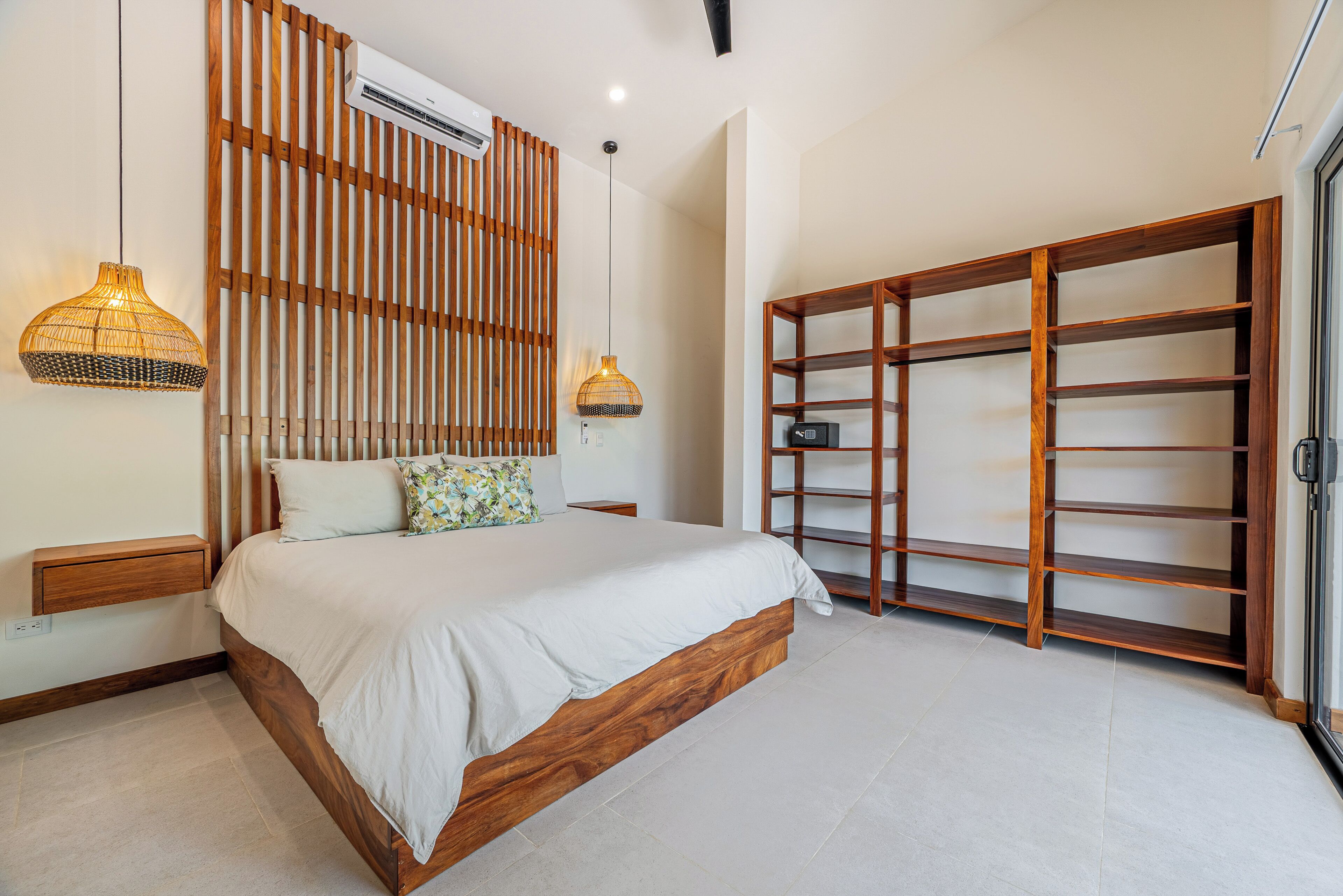 A bedroom with a bed, bedside tables, a wardrobe, and an air conditioning unit.