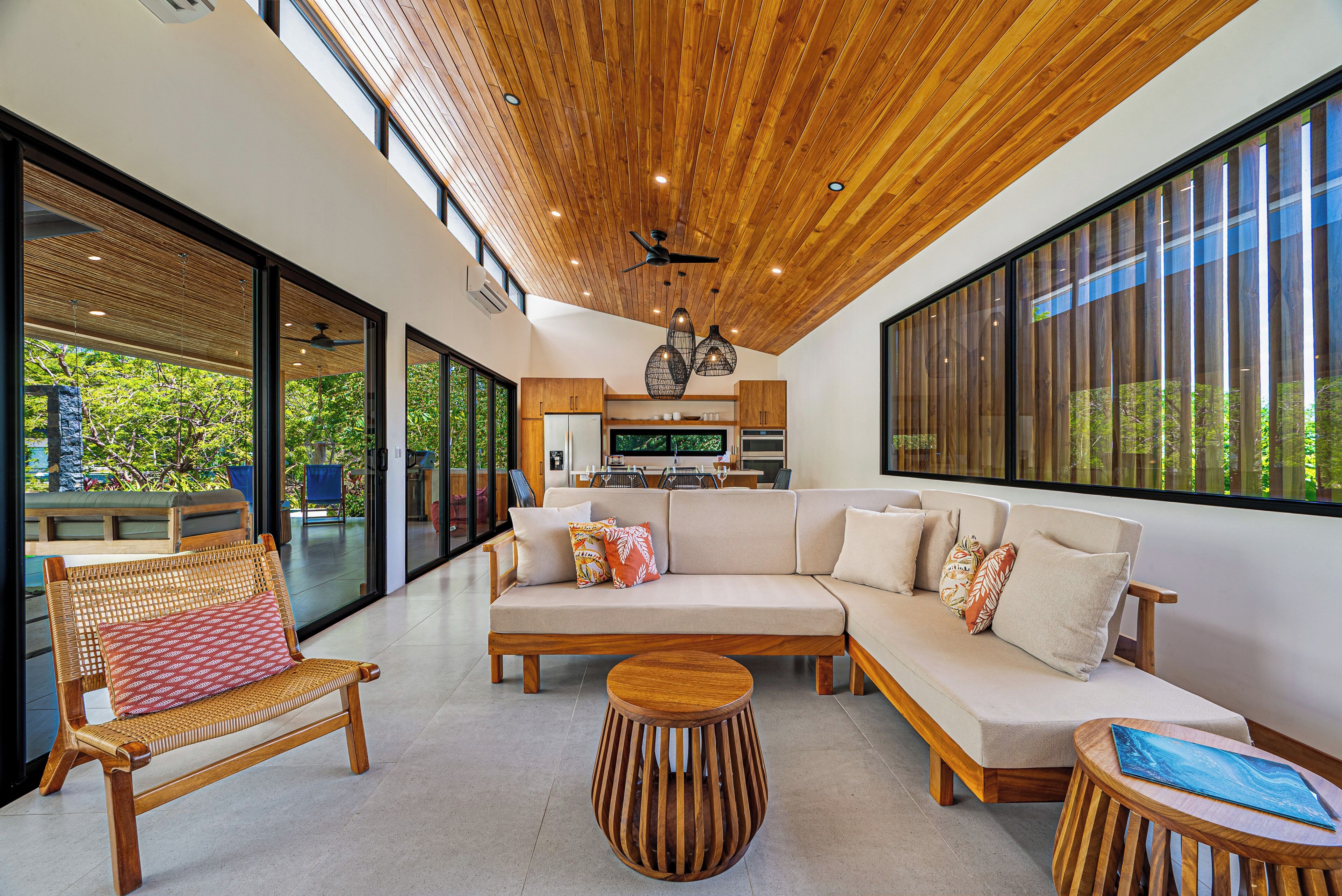 Un intérieur moderne avec un plafond en bois, de grandes fenêtres, un canapé et un coin repas.