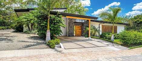 A modern house with a stone facade, a wooden door, and a covered entrance.