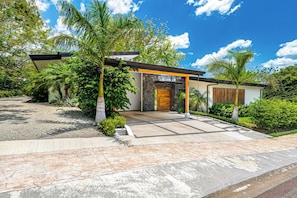 A modern house with a stone facade, a wooden door, and a covered entrance. - Tamarindo Compound w/ Pools & Stunning Views (Tamarindo)