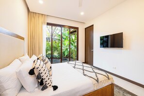 Ein Schlafzimmer mit einem Bett, einem an der Wand befestigten Fernseher und Blick auf Grünfläche.