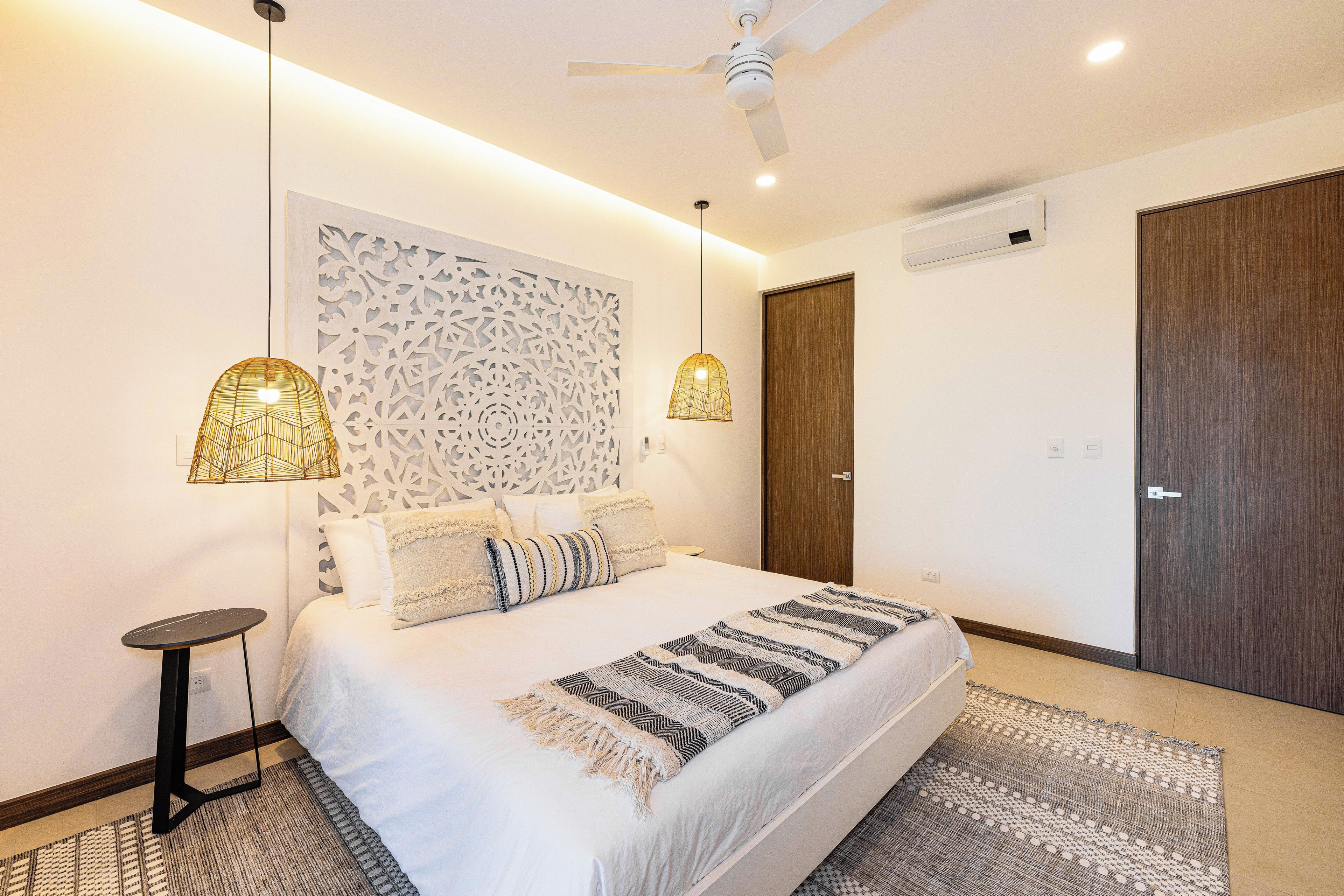 Una camera da letto moderna con un letto grande, due lampade a parete, un ventilatore a soffitto e una porta in legno.