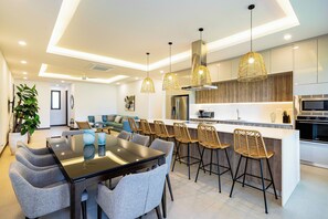 A modern kitchen with a central island, bar stools, and pendant lighting. - Tamarindo Villa w/ Private Pool, Beach Club Access (Tamarindo)
