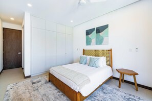 A bedroom with a bed, a nightstand, a wardrobe, and two abstract paintings on the wall. - Tamarindo Villa w/ Private Pool, Beach Club Access (Tamarindo)