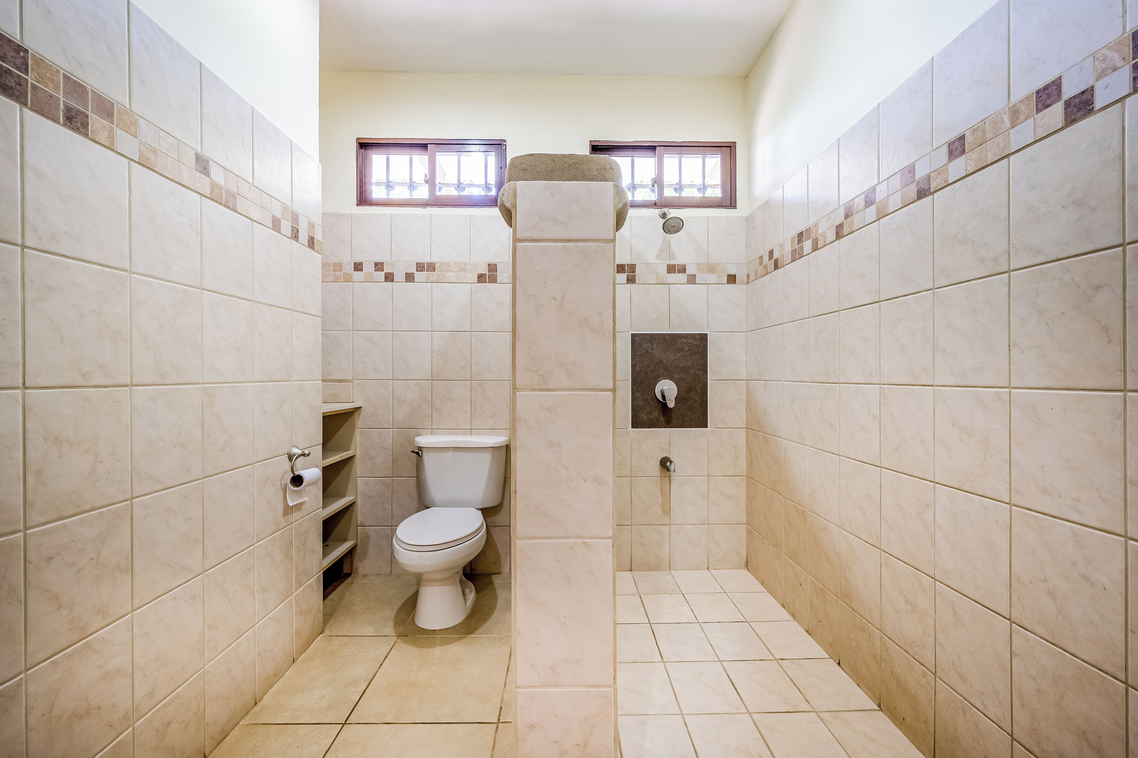 Een kleine badkamer met toilet, douche en raam.
