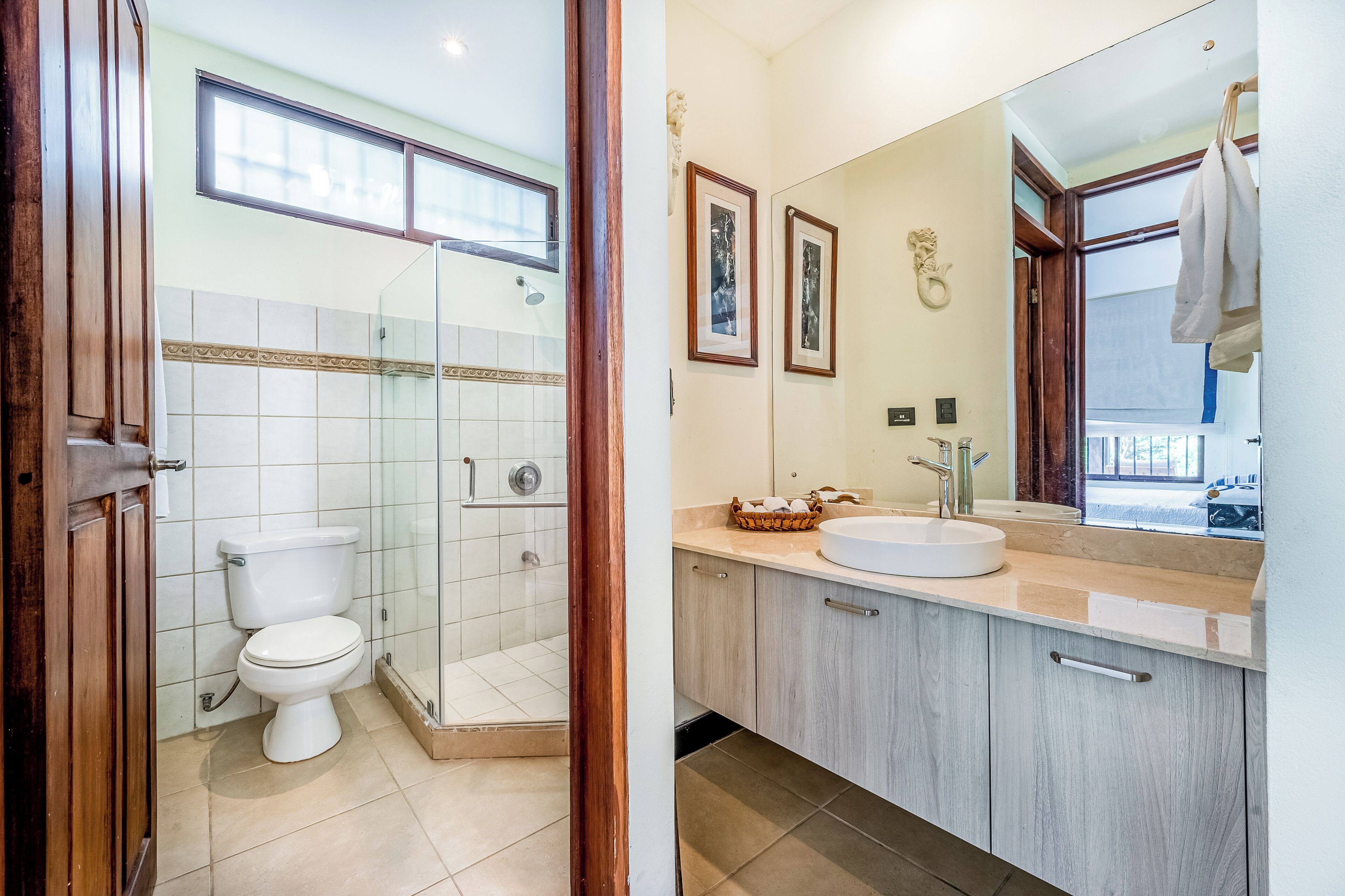 Une salle de bain comprenant des toilettes, une douche fermée par une paroi de verre, un lavabo et un miroir.