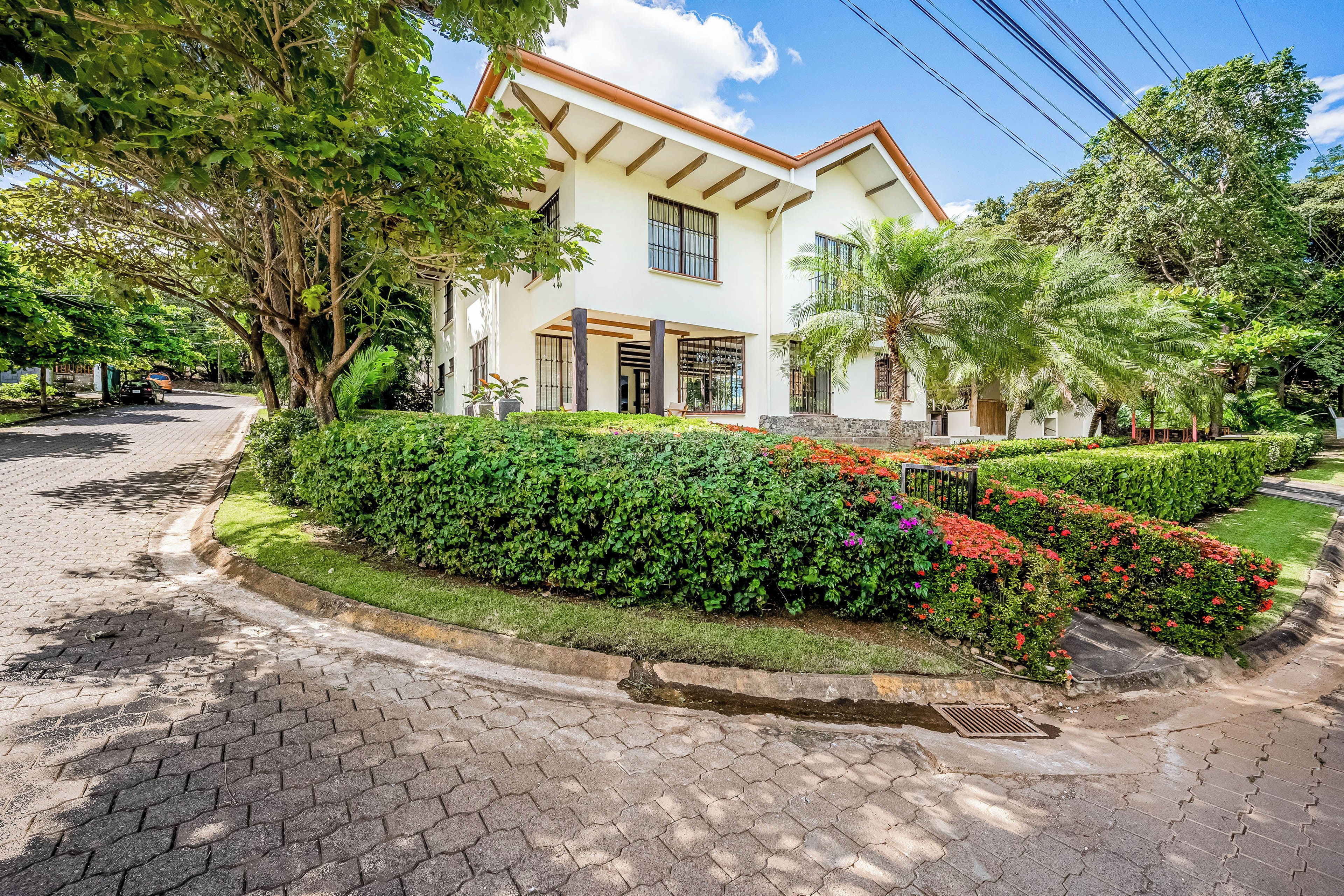 A two-story building with a white facade, a tiled roof, and a paved driveway.