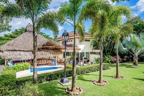 A resort with a pool, thatched-roof structures, and tropical landscaping.
