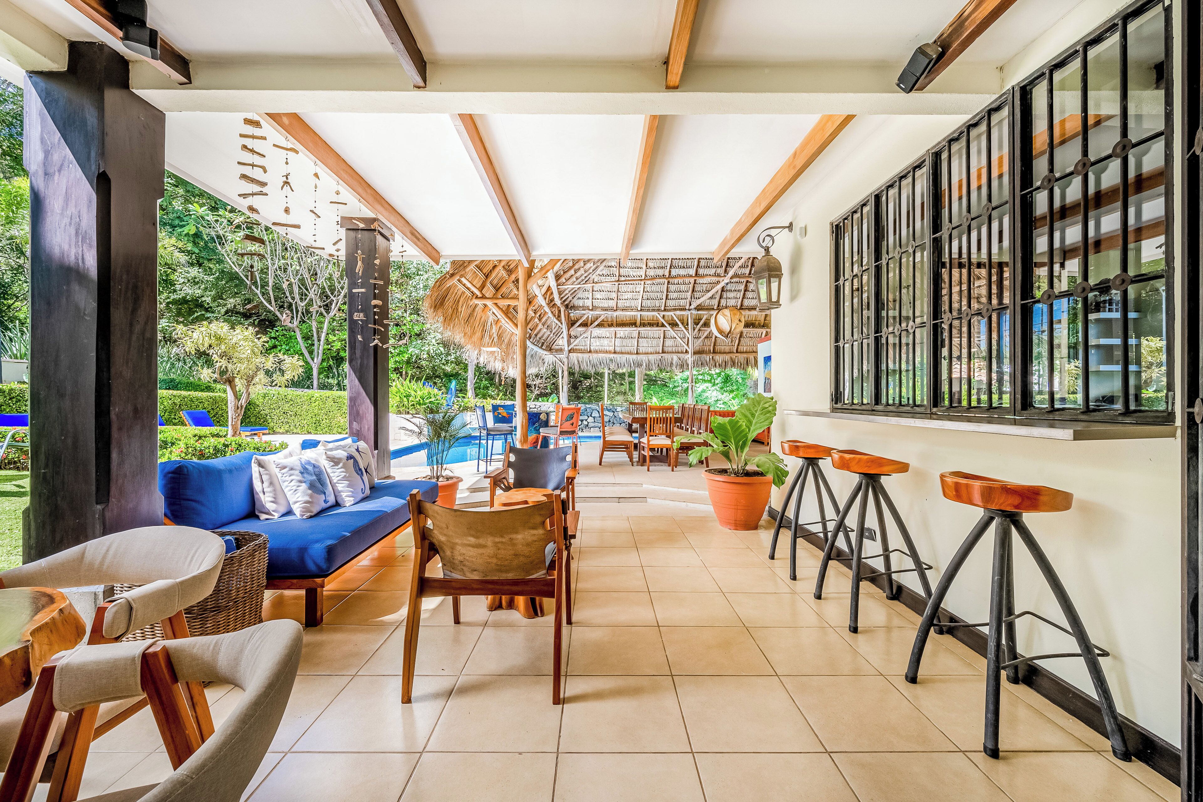A spacious outdoor area with a pool, seating, and a thatched roof structure.