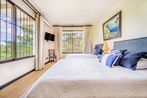 A hotel room with a large bed, a chair, a TV, and a window with curtains.