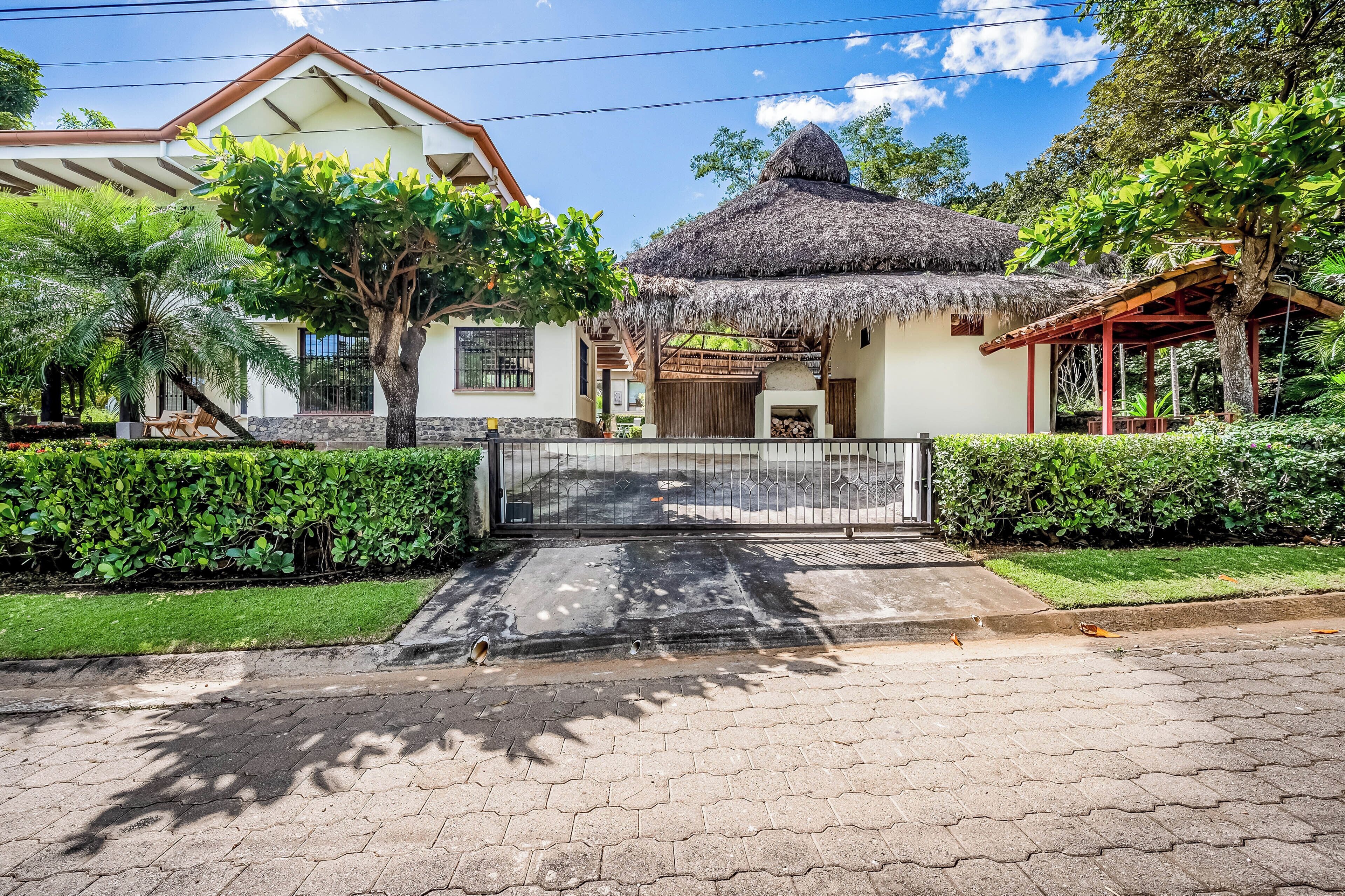 Una casa con techo de paja, entrada empedrada y jardín cuidado.