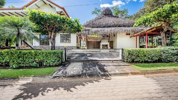 Una casa con techo de paja, entrada empedrada y jardín cuidado.
